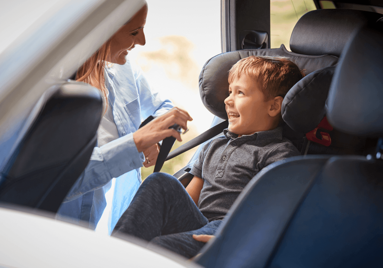 Et barn bliver spændt fast i en autostol i bil af sin mor