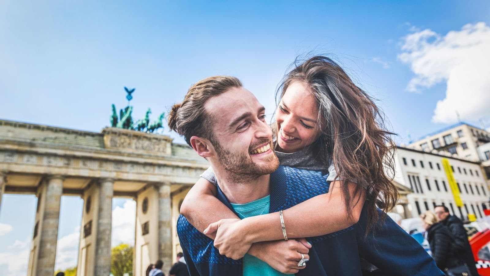 Man and woman hugging and laughing in front of Brandenburger Tor in Berlin