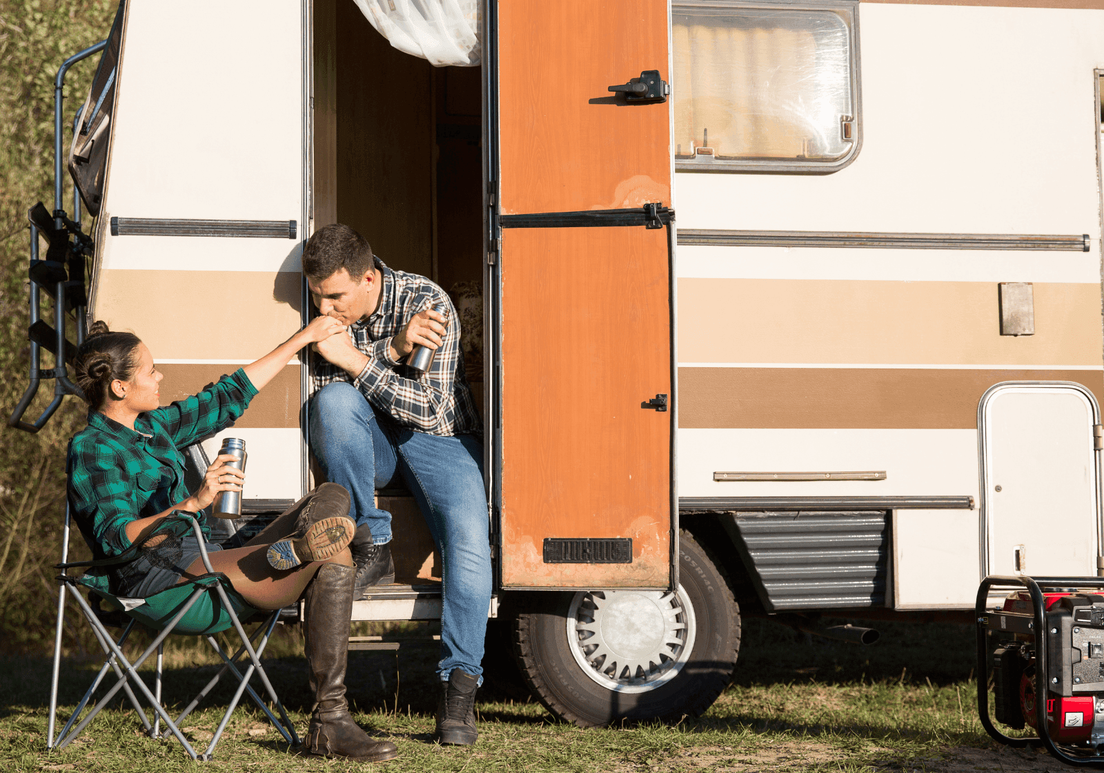 Mand viser sin kærlighed til sin kæreste foran deres retro-camper ved at kysse hendes hånd.