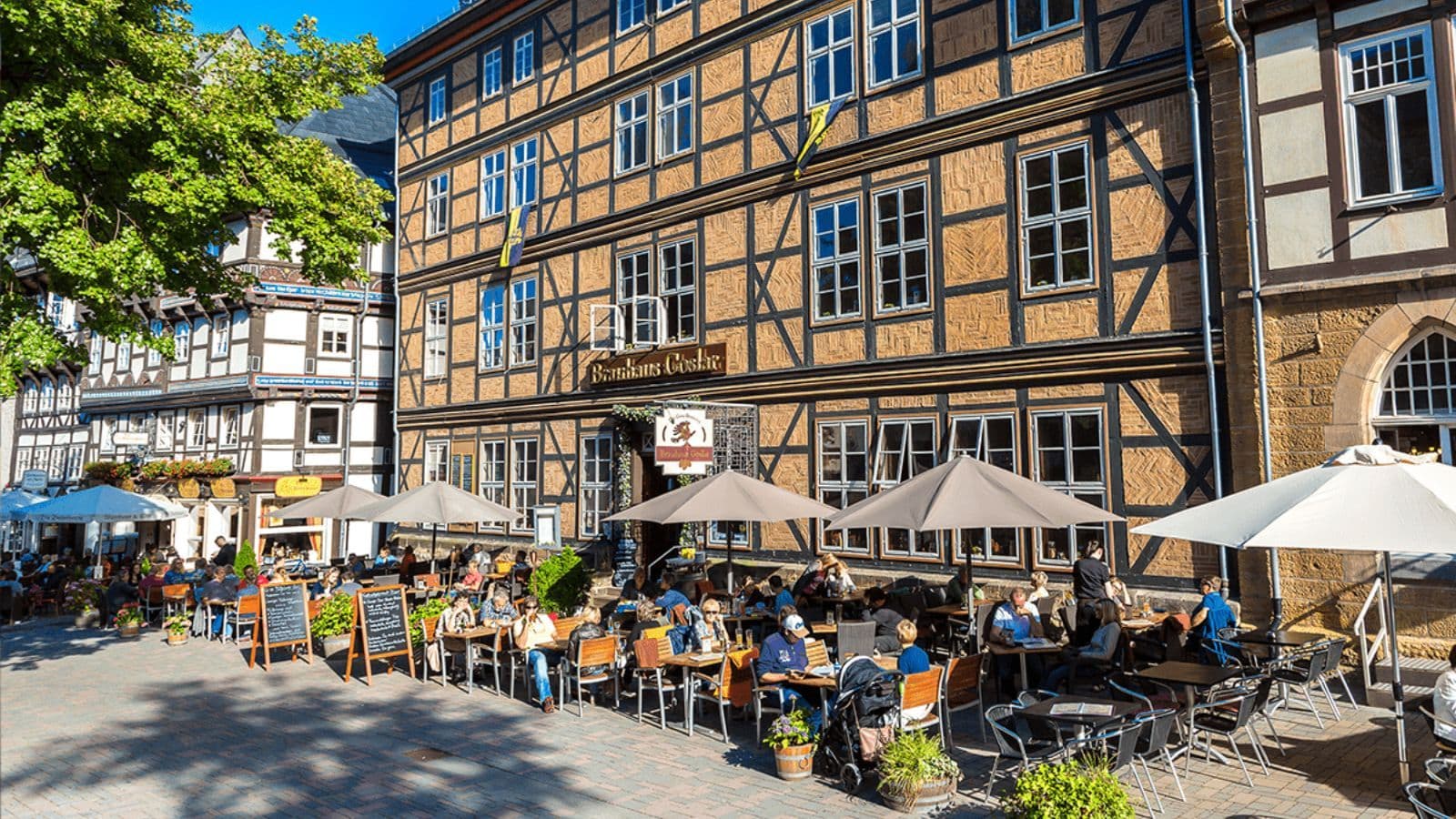 Folk sidder udenfor brauhaus i byen i Harzen og nyder solen og mad